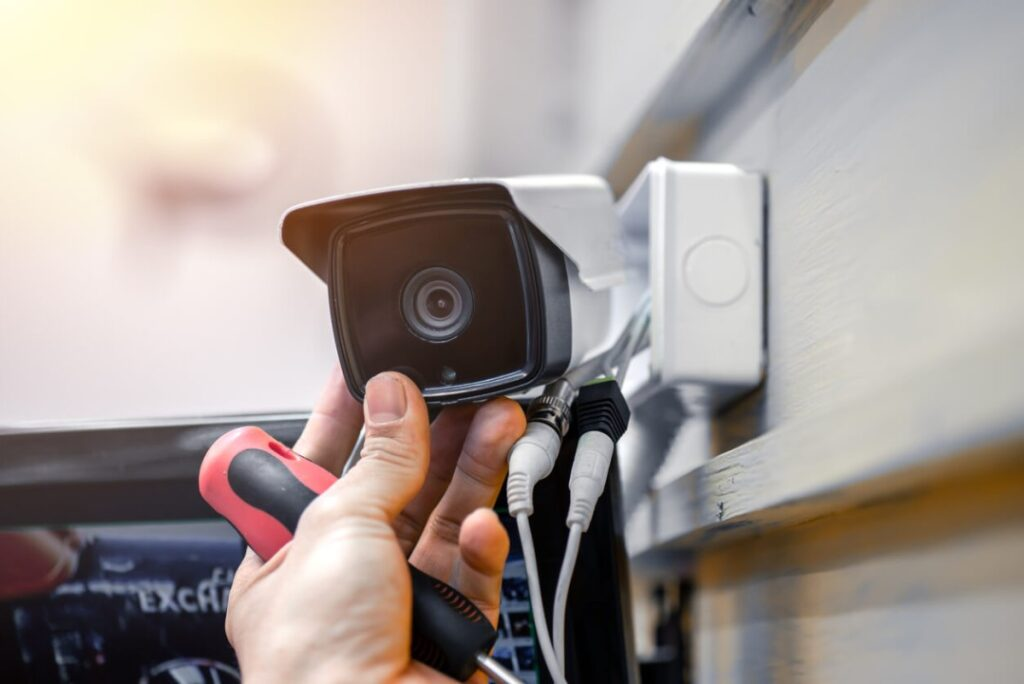 Engineer fitting an exterior bullet CCTV camera to a wall-mounted bracket